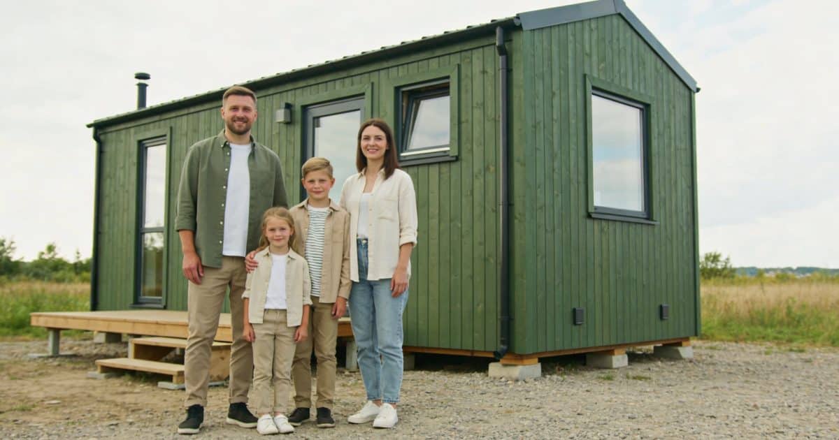 Famille devant petite maison modulaire bois verdoyante