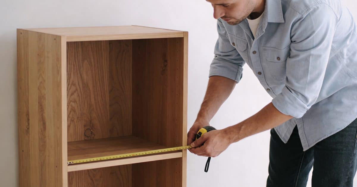 menuisier mesurant un placard vide, planches en bois
