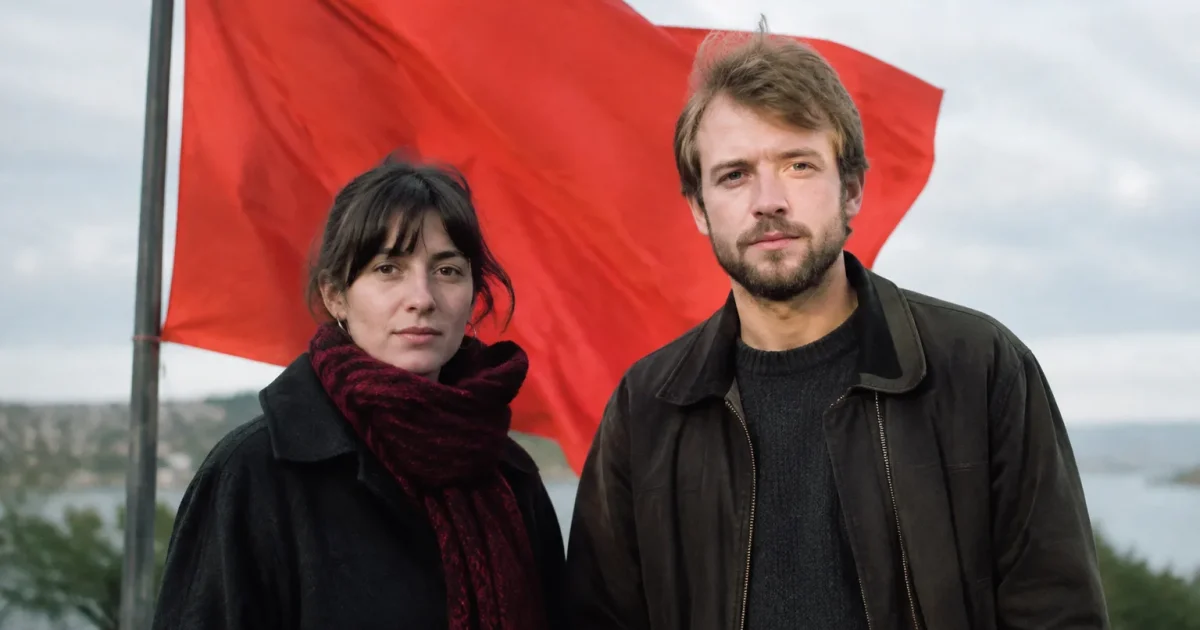Deux personnes debout devant un drapeau rouge