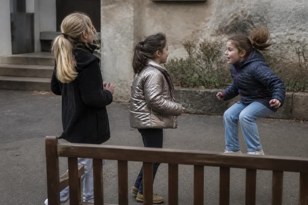 Enfants jouant dans une cour avec banc en bois